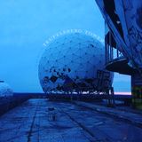 A photograph of a ruined dome structure on the rooftop of a building, with lots of blue tones in the sky and reflected off the concrete.